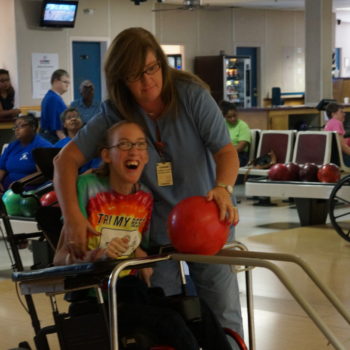 adult female assisting special needs child at a bowling alley