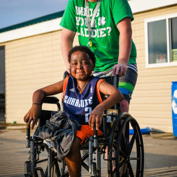Young smiling boy in wheelchair along with caregiver